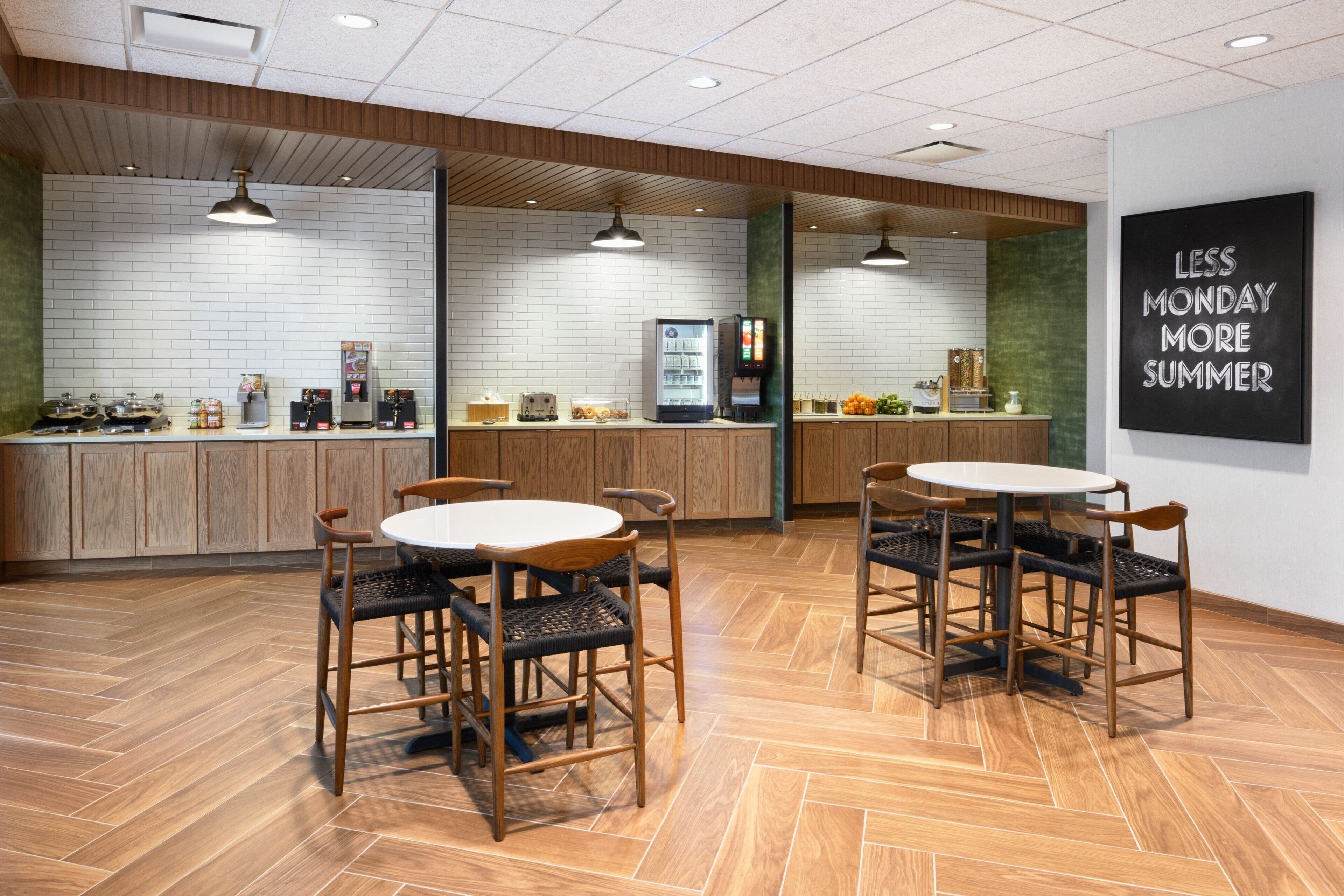 Un espace cuisine moderne avec des meubles en bois, un réfrigérateur, une machine à café et une table à manger avec des chaises.