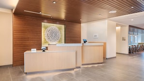 A reception area with a wooden ceiling and a large abstract artwork above the reception desk. - NEW - Fairfield Inn & Suites by Marriott Orlando at Millenia (Orlando)