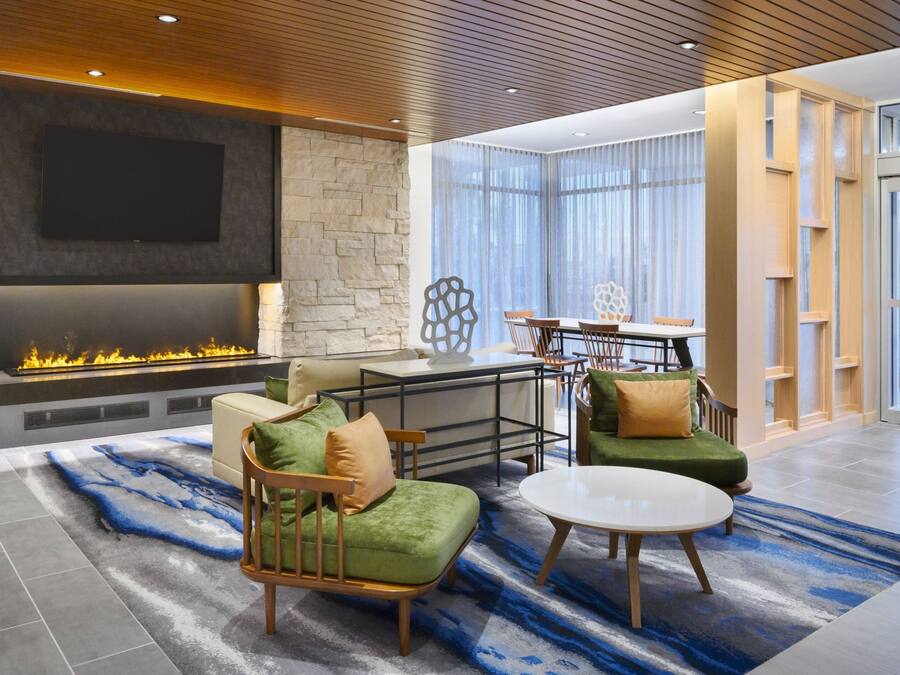 A modern living room with a fireplace, comfortable seating, a dining area, and large windows.