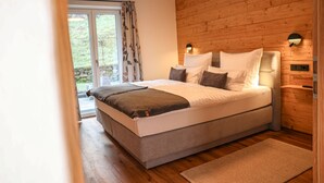 A bedroom with a large bed, wooden walls, a window with curtains, and a nightstand with a lamp.