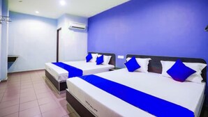 Ein Hotelzimmer mit zwei Betten, jeweils mit blauer Bettdecke und weißen Kissen.