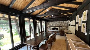 A spacious dining area with a long wooden table and chairs, a stone fireplace, and large windows offering a view of the outdoors. - Holiday village Horlog Castle (Devin)