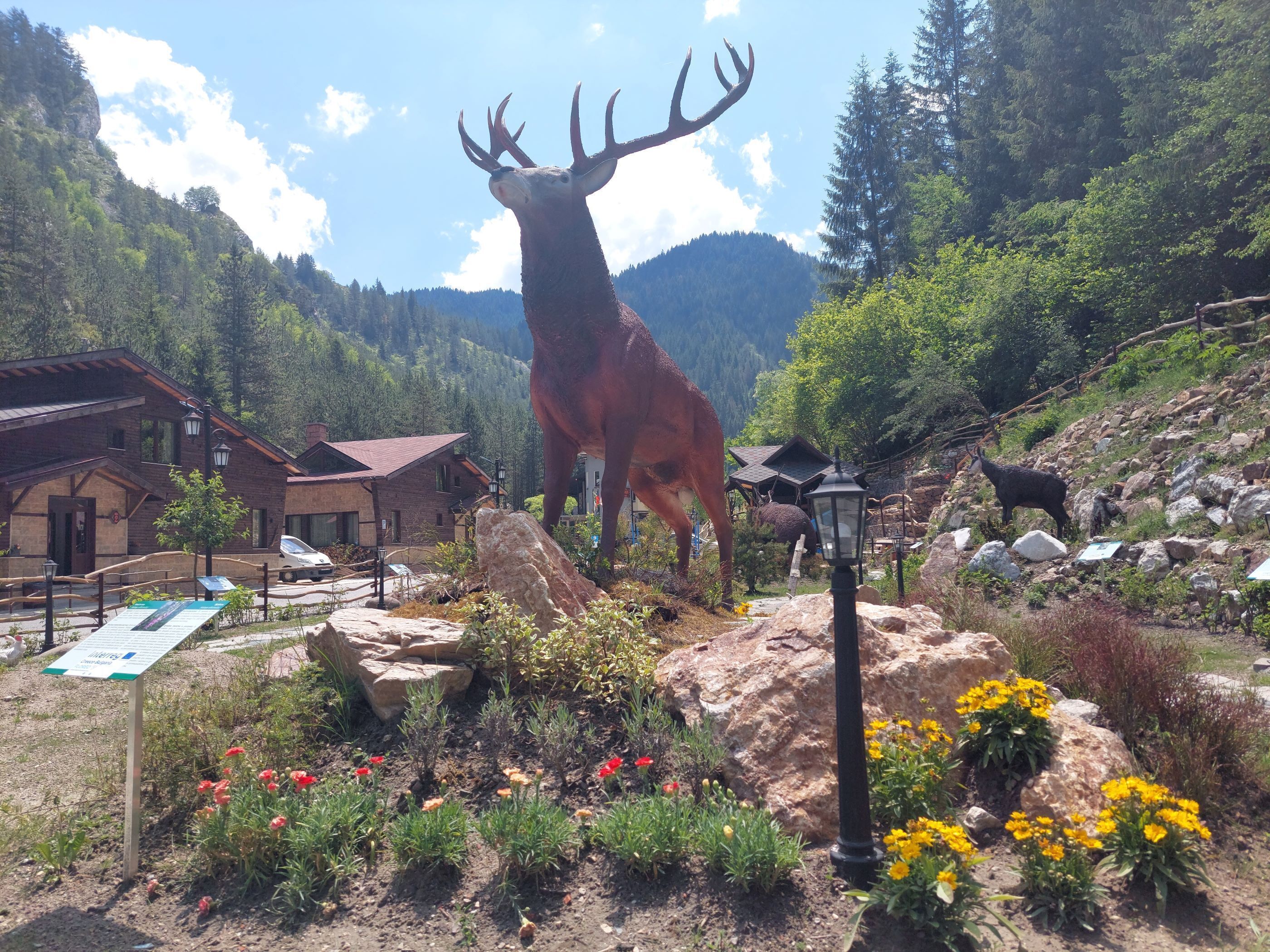 A large elk statue in a park with buildings and mountains in the background.