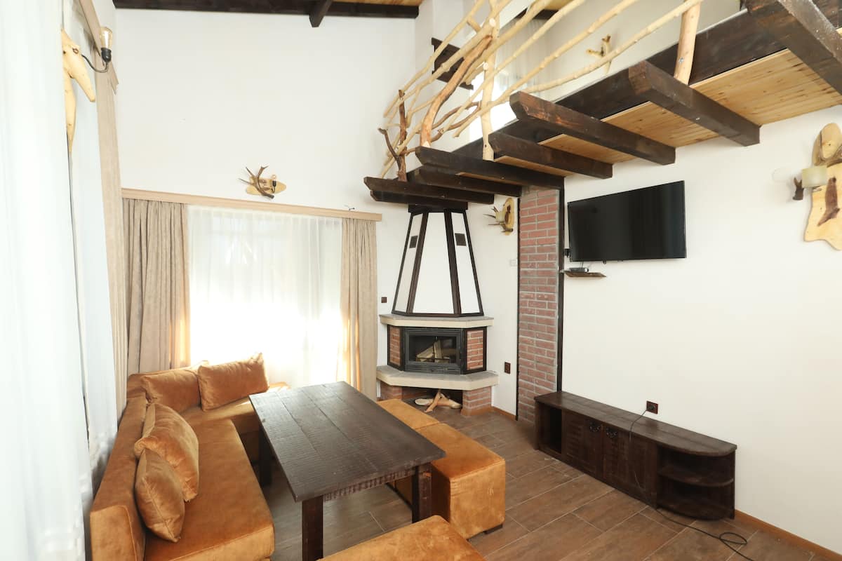 A cozy living room with a wooden table, sofa, and a fireplace.