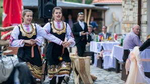 Two individuals in traditional attire performing in an outdoor setting with tables and chairs, suggesting a cultural event or celebration. - Holiday village Horlog Castle (Devin)