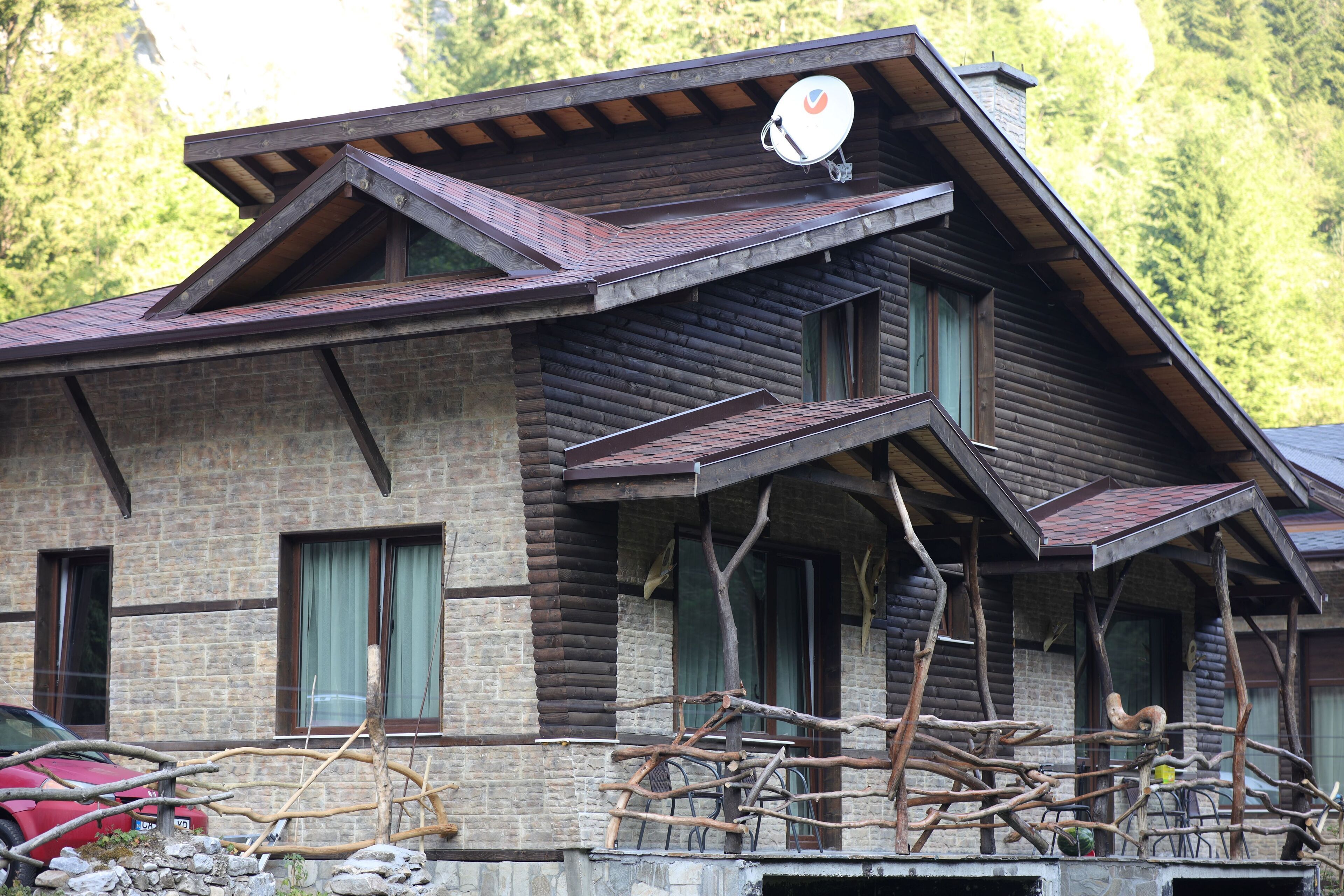 Eine Blockhütte mit geneigtem Dach, einer Satellitenschüssel und einem Steinfundament.