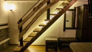 A wooden staircase with built-in lighting, a stone wall, and a wooden bench.