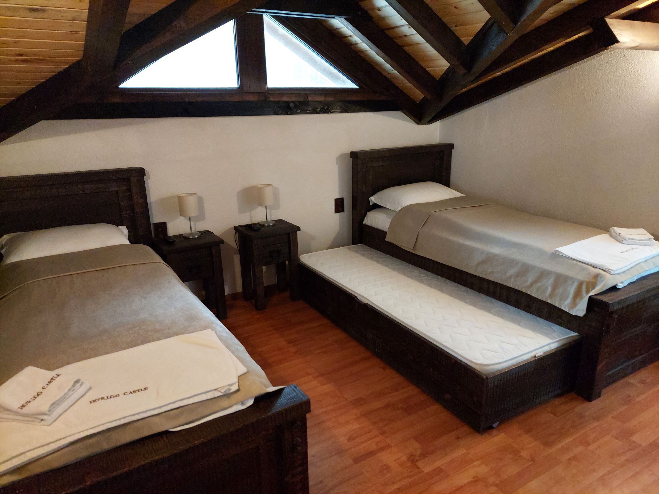Une chambre avec deux lits, des têtes de lit en bois et un puits de lumière.