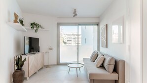 A modern living room with a sofa, a TV, a coffee table, and potted plants. - Kristall 9  (Massagno)