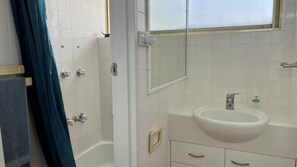 Un baño con bañera, lavabo y espejo.