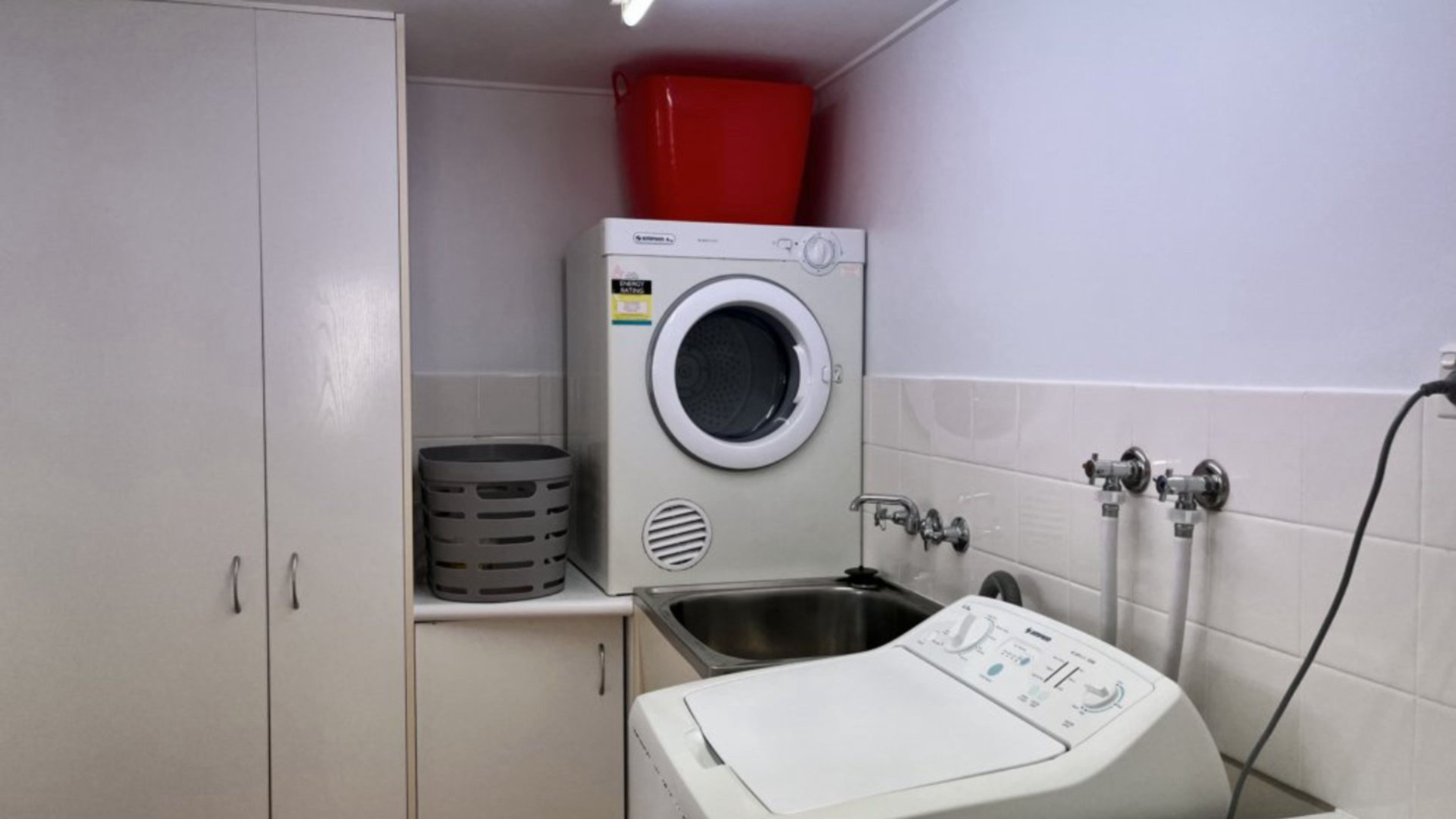 A laundry room with a washing machine, a dryer, and a sink.