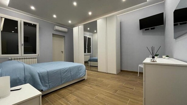 A modern bedroom with a bed, a desk, and a TV. - PARADISE HOME (Augusta)