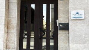A hotel entrance with a dark wooden gate, a sign reading "PARADISO," and a number "13" above the gate. - PARADISE HOME (Augusta)