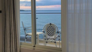 Ein Balkon mit Blick auf das Meer, ein weißer Stuhl und ein weißer Tisch.