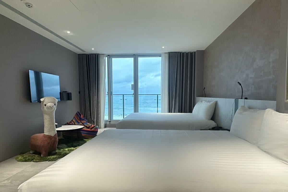 Ein modernes Hotelzimmer mit einem großen Bett, einem Flachbildfernseher, einer weichen Llamajagd und Blick auf den Ozean.