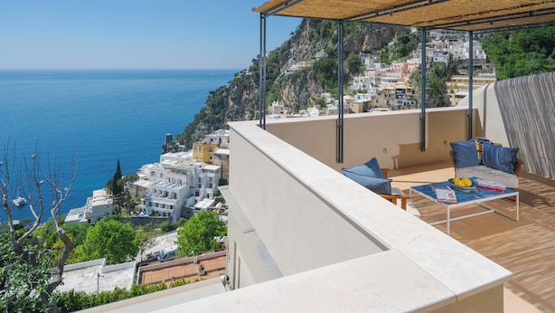 A balcony with a view of the sea and a hillside town.