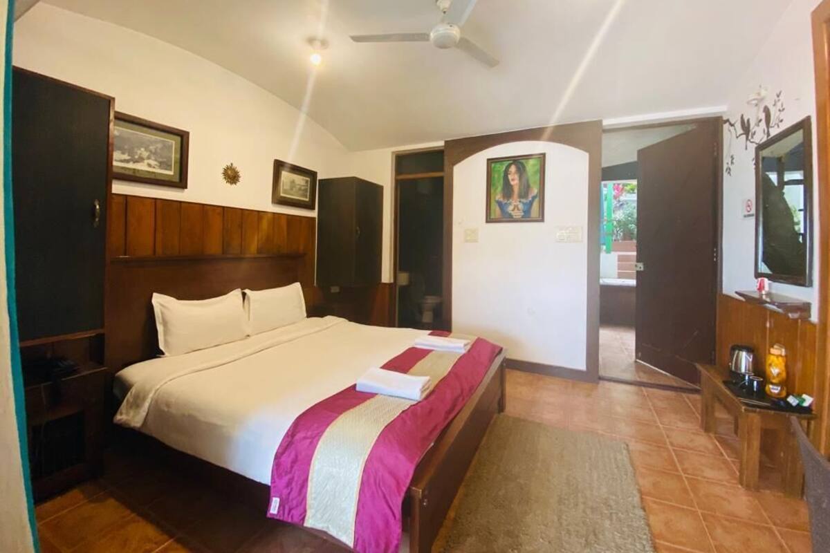 Ein Hotelzimmer mit einem großen Bett, einem Holz-Kopfteil, einem Deckenventilator und einem Fernseher an der Wand.