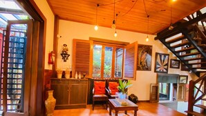 Un ambiente accogliente con una scala in legno, una zona salotto con cuscini e vista panoramica attraverso ampie finestre.