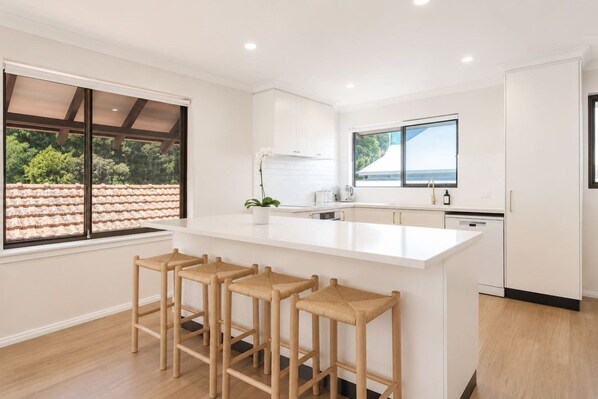 A modern kitchen with a large island, bar stools, and a view of the roof.