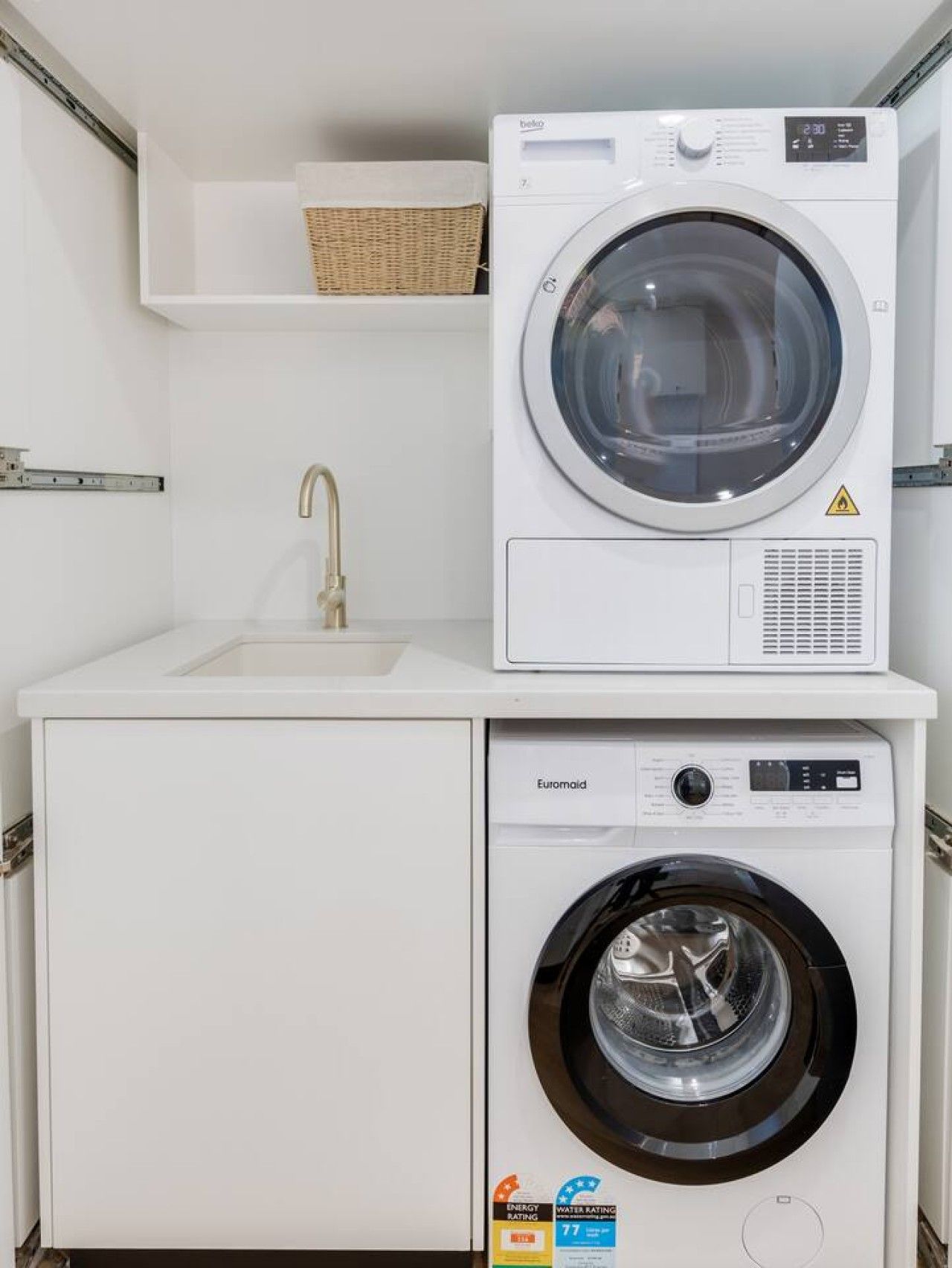 A compact laundry area with a washing machine and dryer, a sink, and a shelf above the dryer.