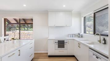 A modern kitchen with white cabinetry, a built-in oven, and a window providing a view of the outdoors.