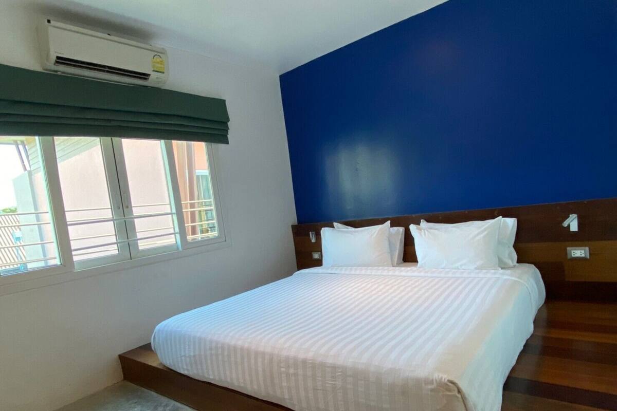 Une chambre d’hôtel avec un lit, une fenêtre avec des stores et un appareil de climatisation.