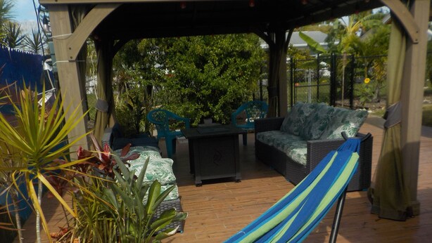 Eine Terrasse im Freien mit einer Hängematte, Korbmöbeln und Blumentöpfen.