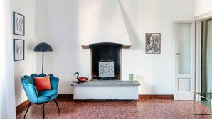 A room with a fireplace, a blue armchair, and a floor lamp. - STELLA APARTMENT  (Como)