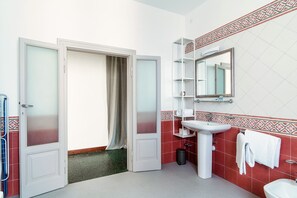 Un baño con lavamanos blanco, un espejo y un perchero para toallas.