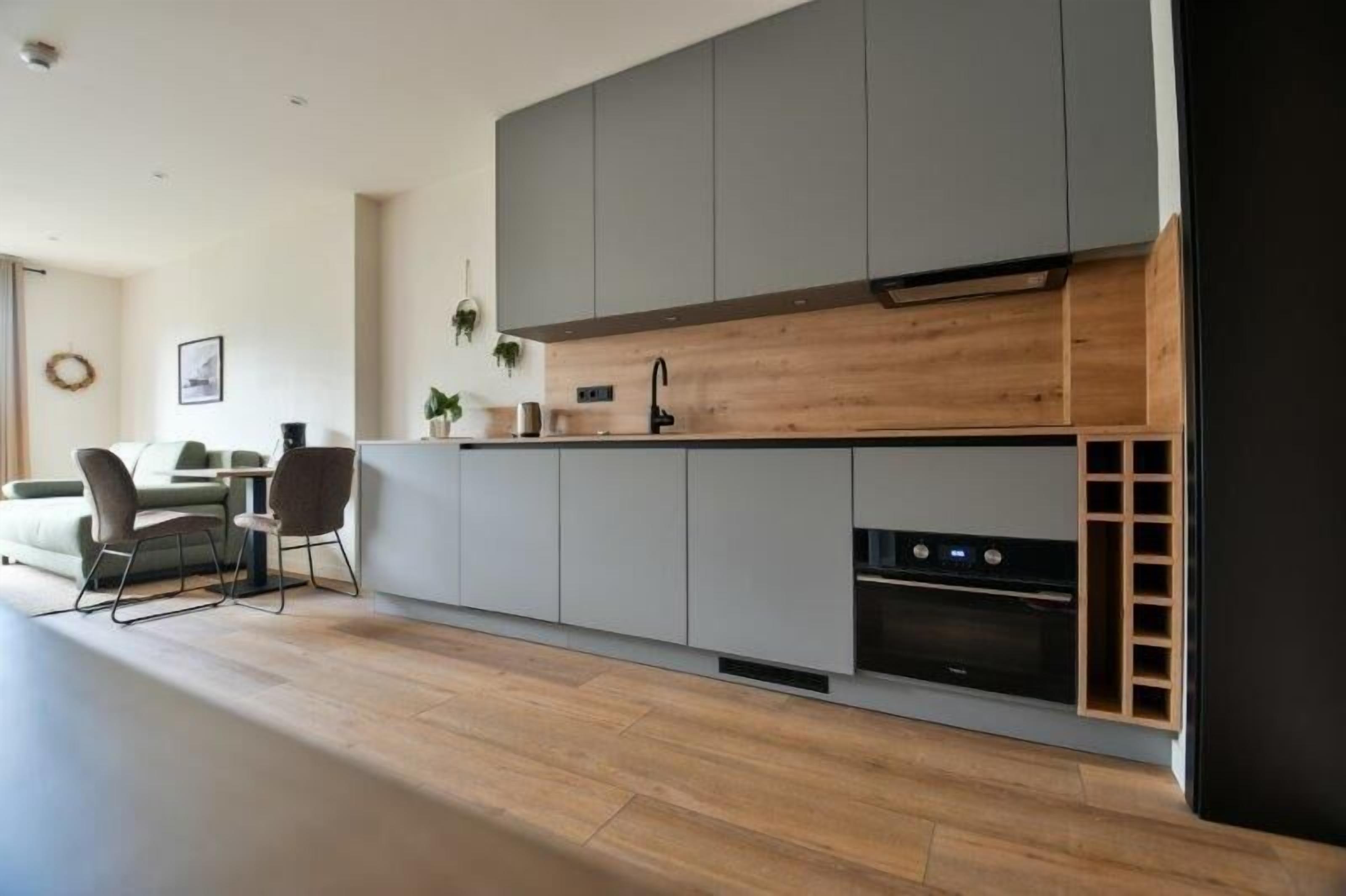 Una cocina moderna con armarios grises, encimera de madera y electrodomésticos integrados.