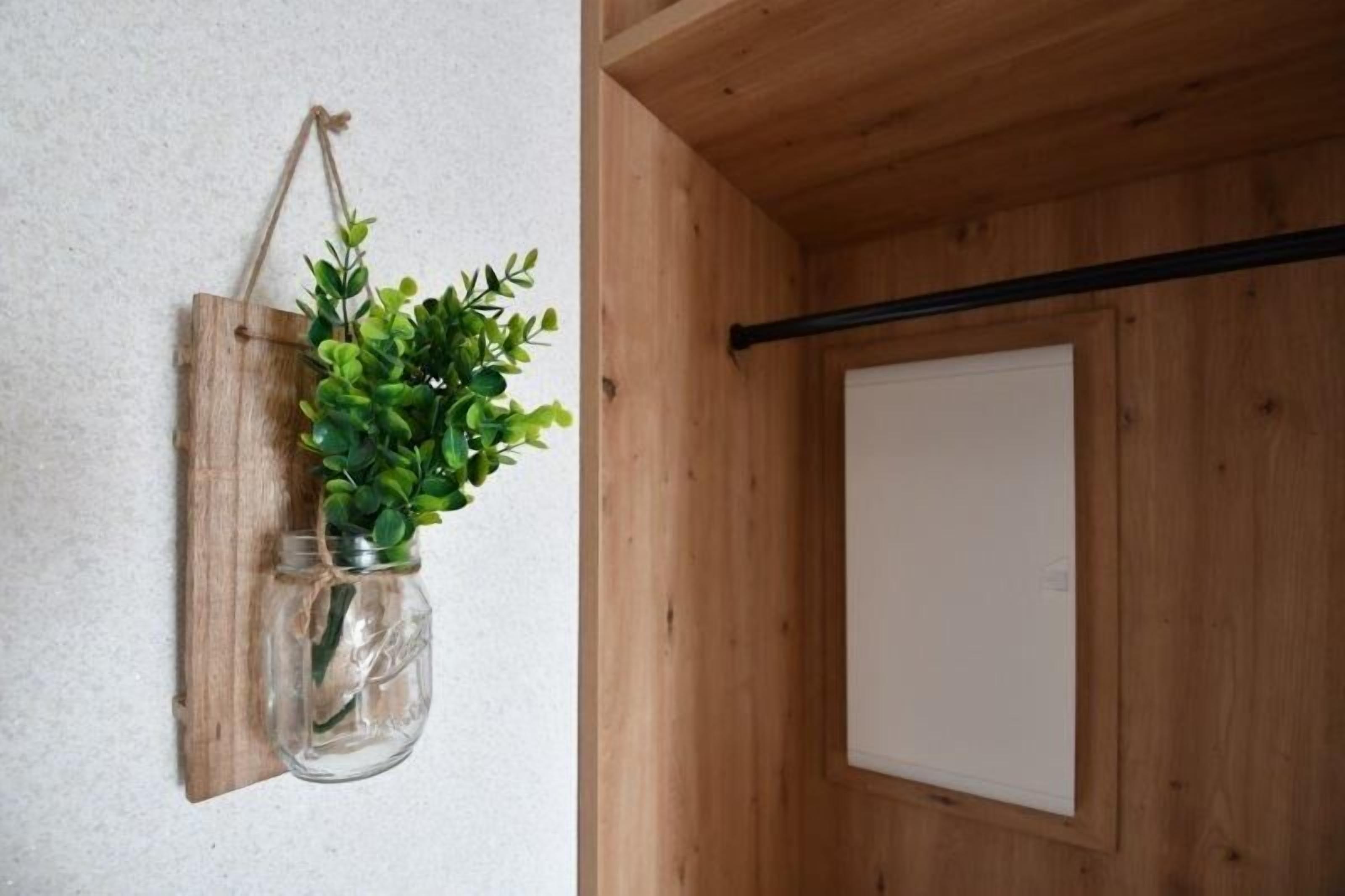 A rustic wooden wall with a hanging plant in a mason jar.