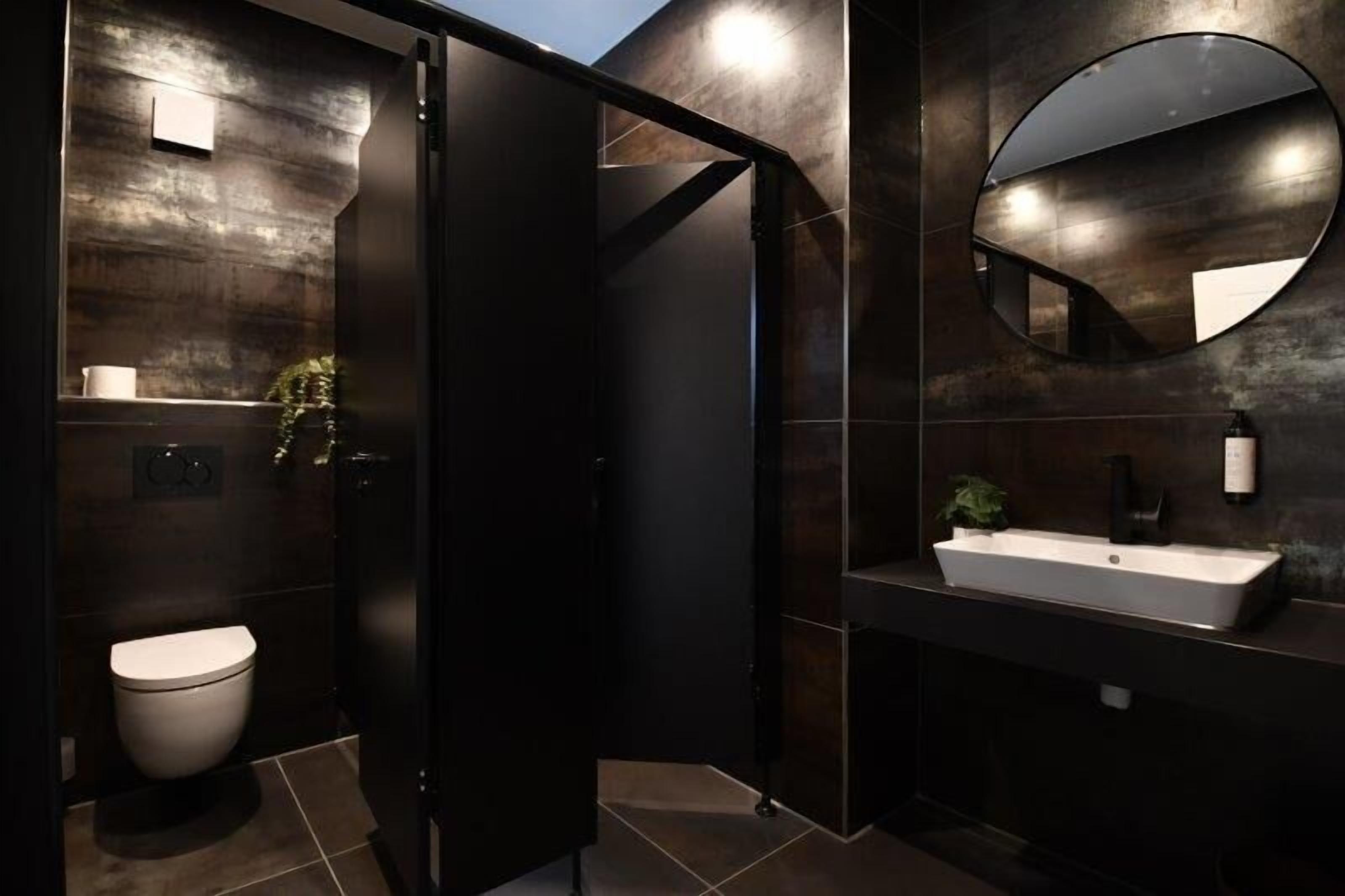 A modern bathroom with a toilet, a sink, and a mirror.