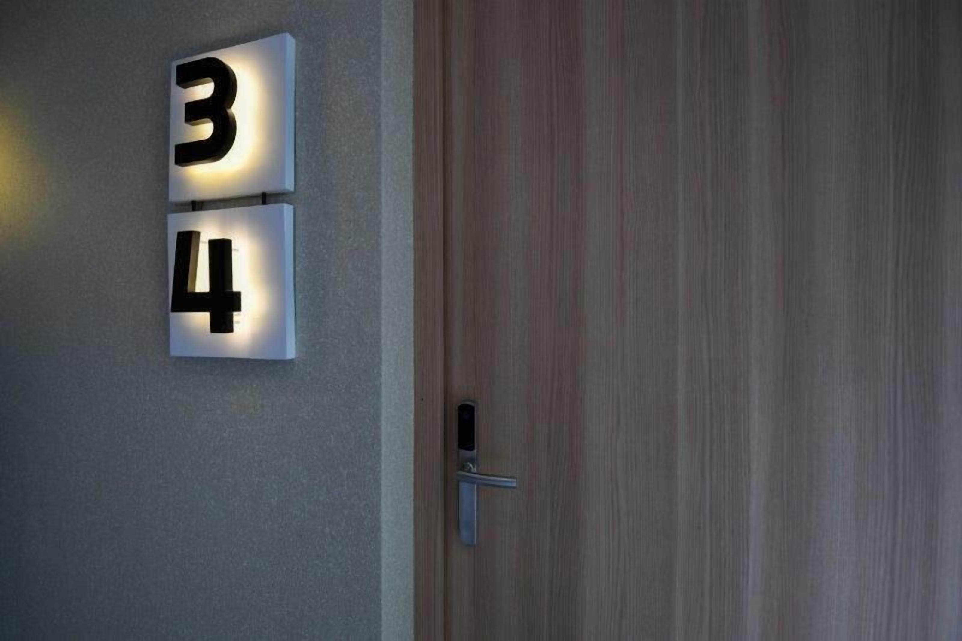 A door with a numeric keypad and a wall-mounted light fixture displaying the numbers 34.