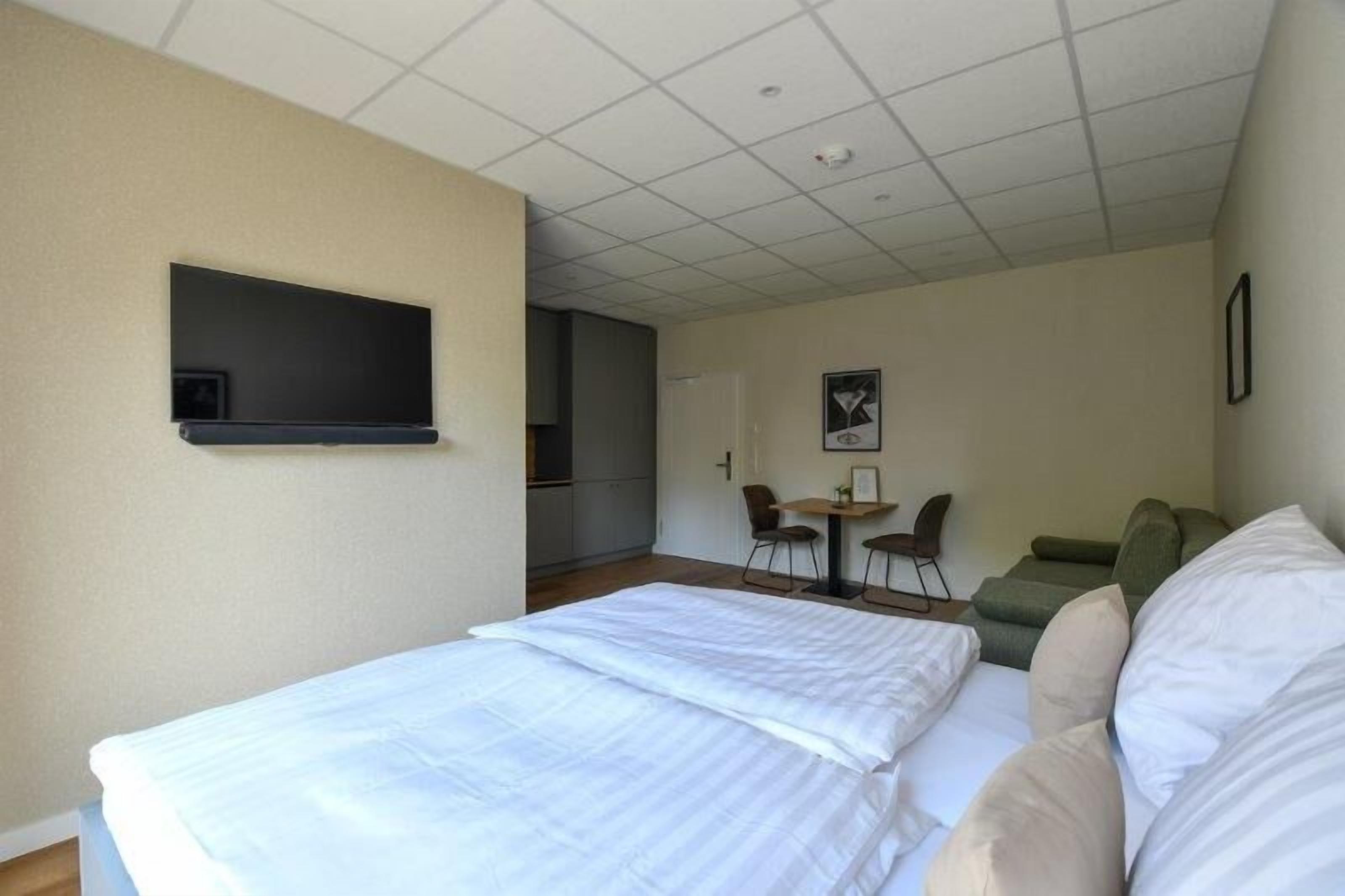 A hotel room with a bed, a small desk, a chair, and a couch.