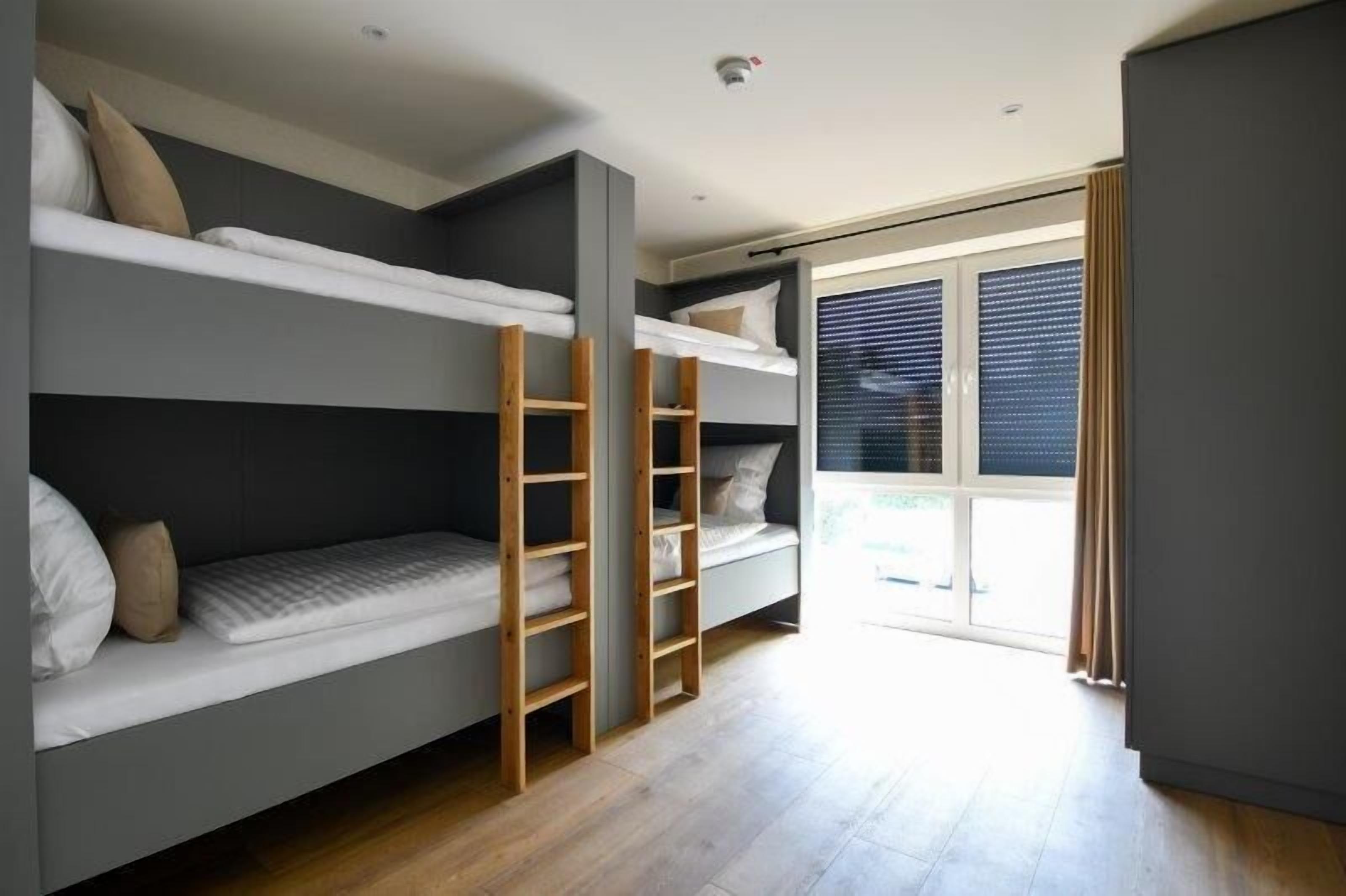 Una habitación moderna con literas, un ventanal grande y una puerta corredera.