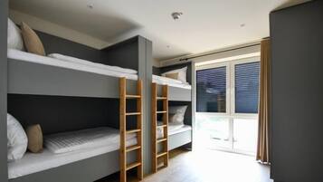 Una habitación moderna con literas, un ventanal grande y una puerta corredera.