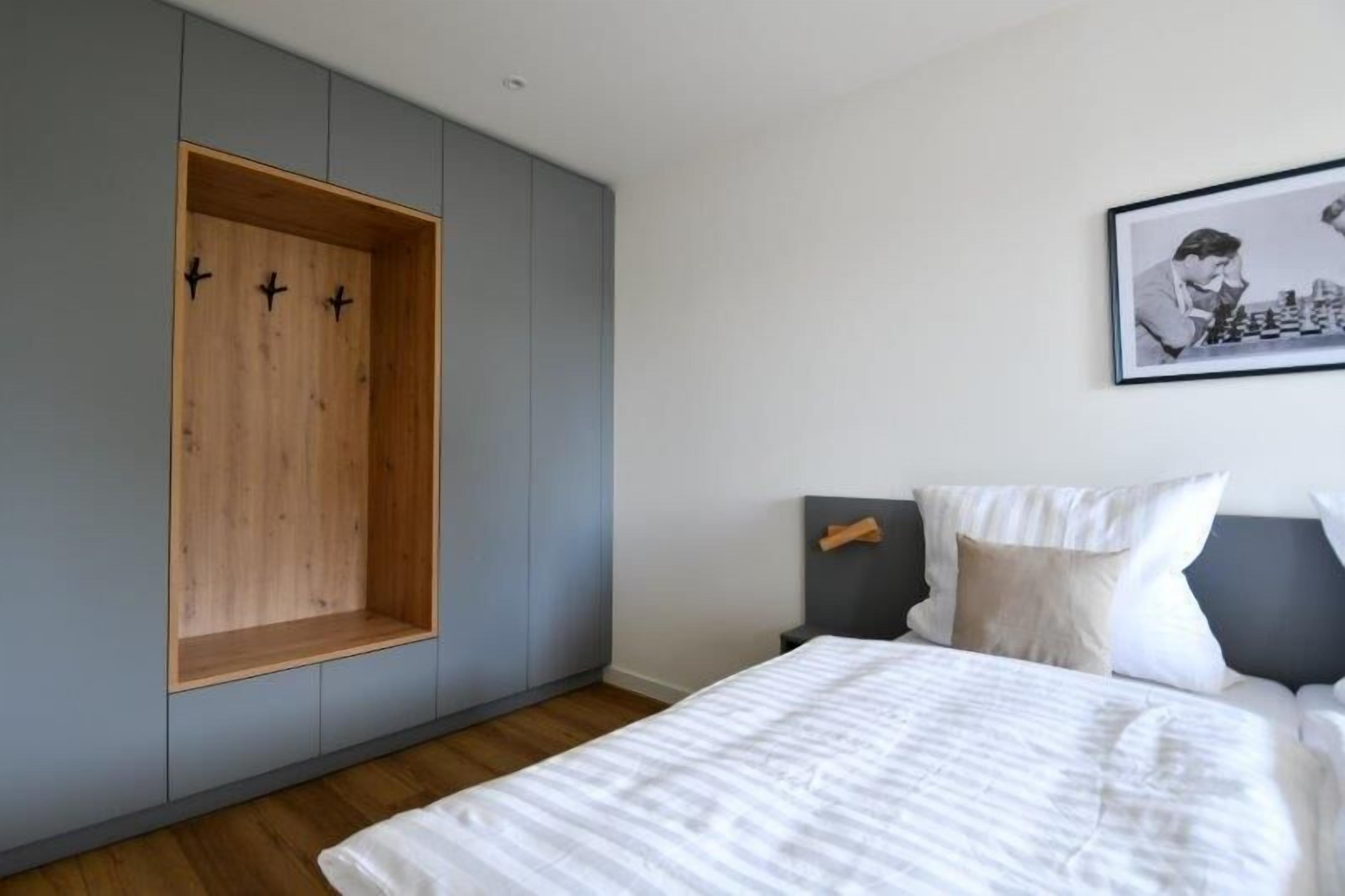 Un dormitorio con cama, un armario gris y un cuadro en la pared.