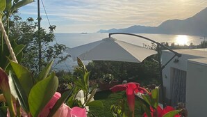 Une vue d’une zone côtière avec une étendue d’eau, des montagnes à l’horizon et un pont.