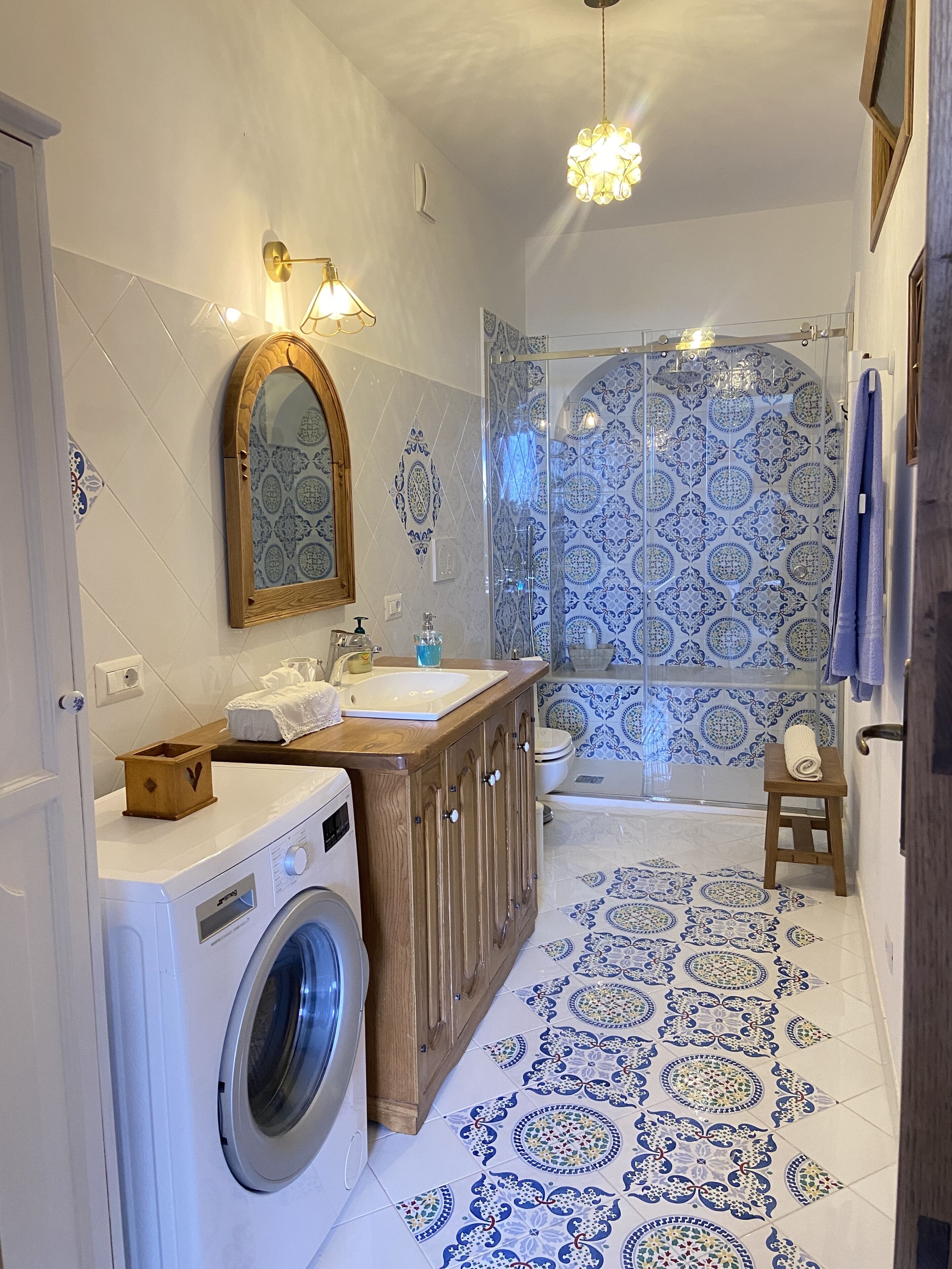 Un baño con lavadora, lavamanos, espejo y ducha.