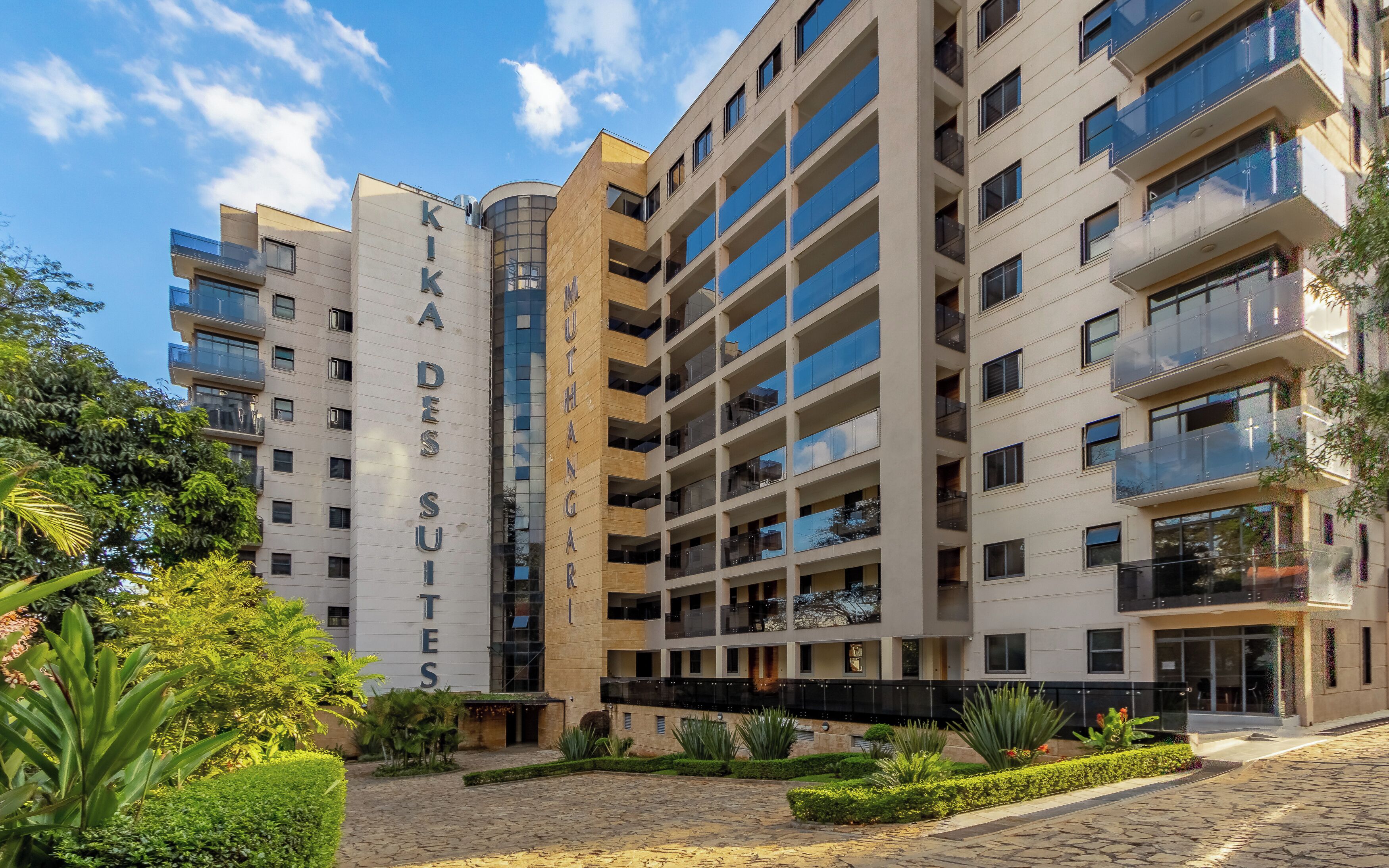 A multi-story hotel with a modern architectural design, featuring balconies and a courtyard with landscaping.