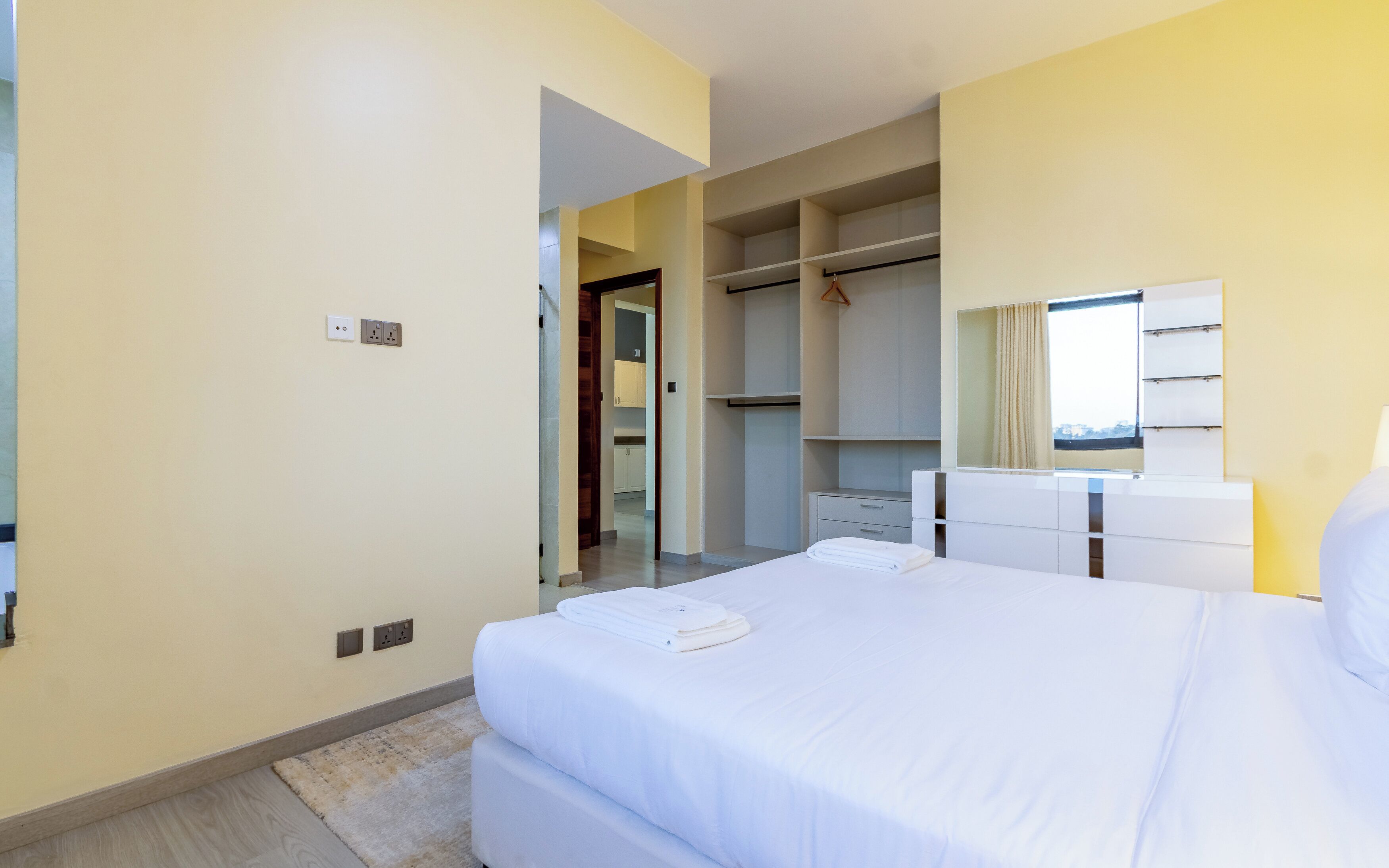 A hotel room with a bed, a wardrobe, a mirror, and a window.