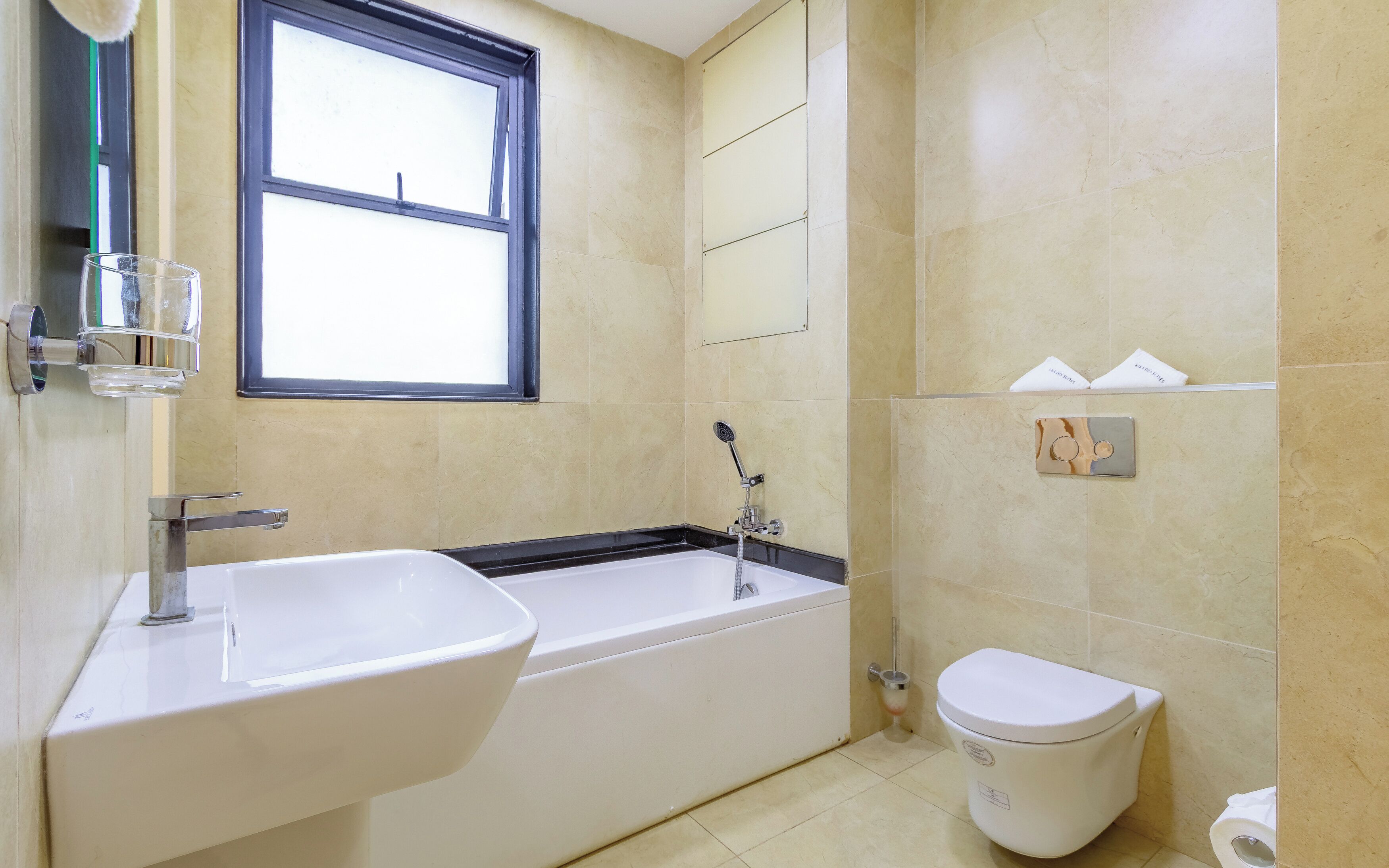Un bagno con vasca, lavandino, water e finestra.