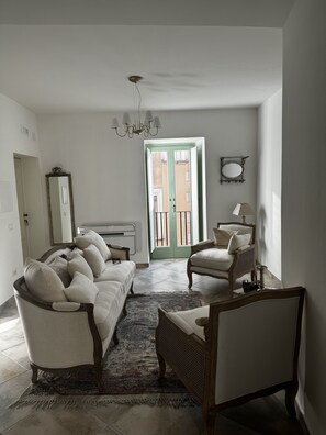 Relax in this spacious living room with a comfortable sofa set, matching armchair, and patterned area rug. Enjoy the open feel and views from the sliding glass door leading to the outdoor balcony.