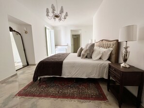 Cozy retreat with a large bed, chandelier, and nightstand, perfect for a restful stay.
