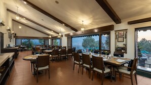 Un comedor amplio con techos altos, ventanas grandes y varias mesas y sillas.