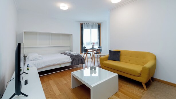 Ein modernes Hotelzimmer mit Bett, einer Couch, einem Couchtisch und einem Fernseher.