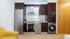 Eine kompakte Küche mit Kühlschrank, Backofen, Geschirrspüler und Waschmaschine.