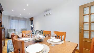 A dining area with a wooden table set for four, chairs, and a buffet with bread.