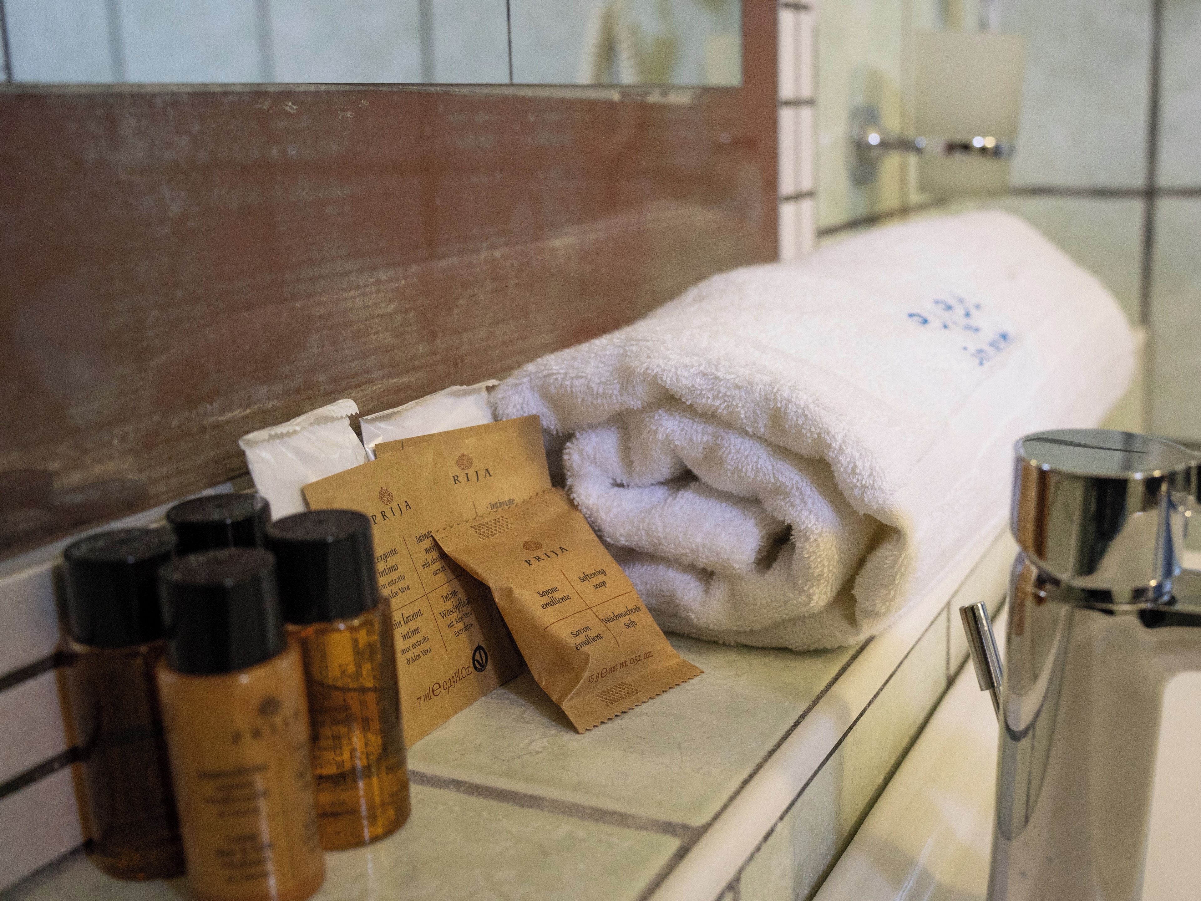 A bathroom with a white towel, toiletries, and a mirror.