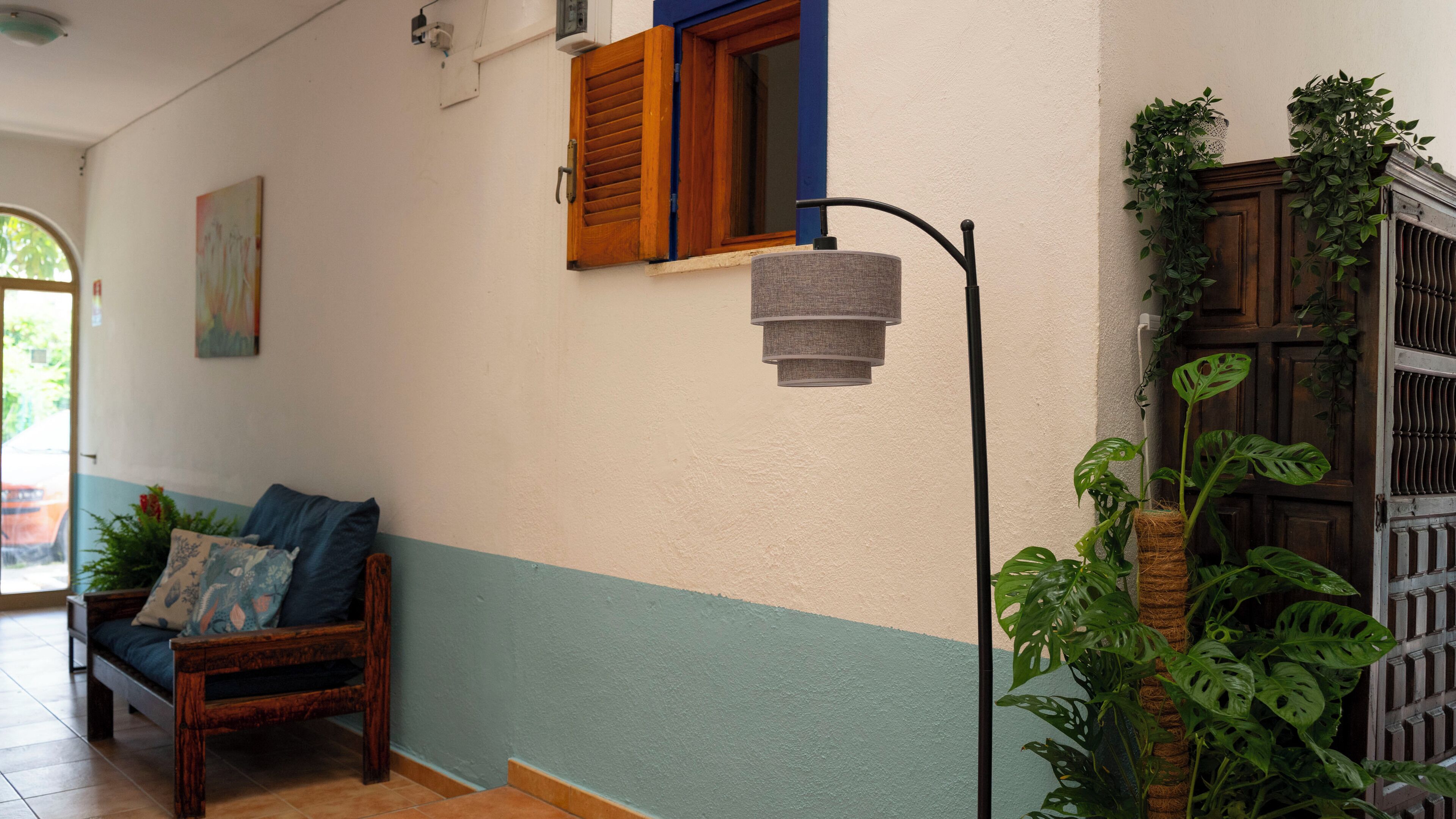 A room with a wooden bench, a wall-mounted lamp, and a window with wooden shutters.